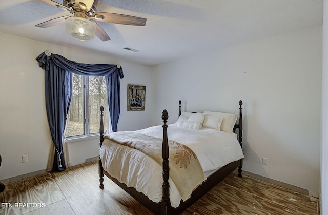 bedroom featuring visible vents, baseboards, ceiling fan, and wood finished floors