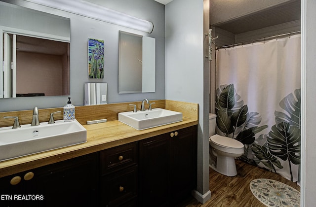 full bath featuring double vanity, toilet, wood finished floors, and a sink