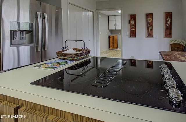 kitchen featuring black electric cooktop and stainless steel fridge