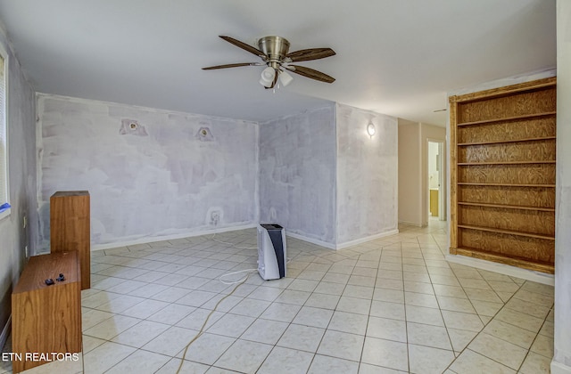 spare room featuring light tile patterned flooring, built in shelves, baseboards, and ceiling fan