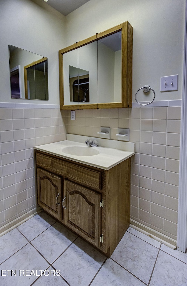 bathroom with tile patterned flooring, a wainscoted wall, tile walls, and vanity