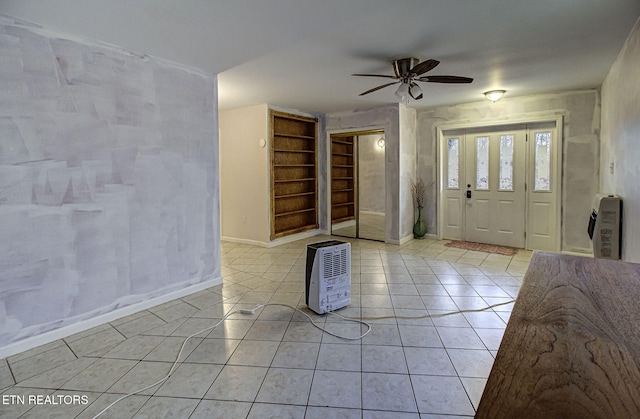 foyer entrance with heating unit, a ceiling fan, baseboards, and light tile patterned floors