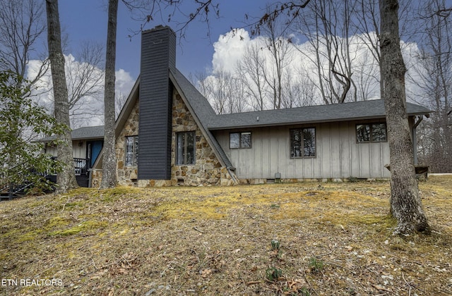 exterior space featuring crawl space, stone siding, board and batten siding, and a chimney