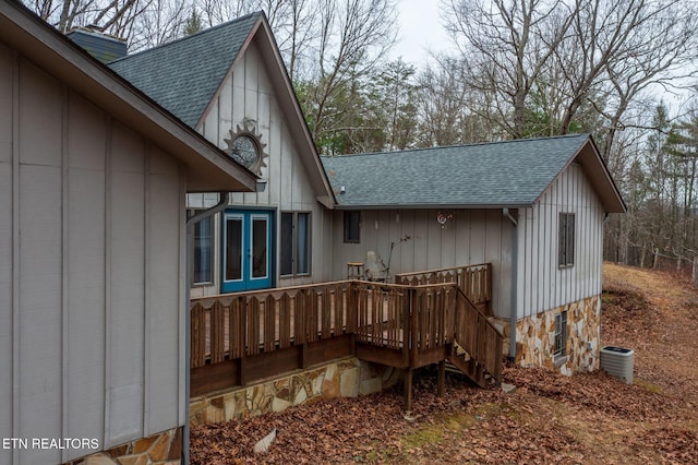 back of property with central AC, board and batten siding, roof with shingles, and a wooden deck