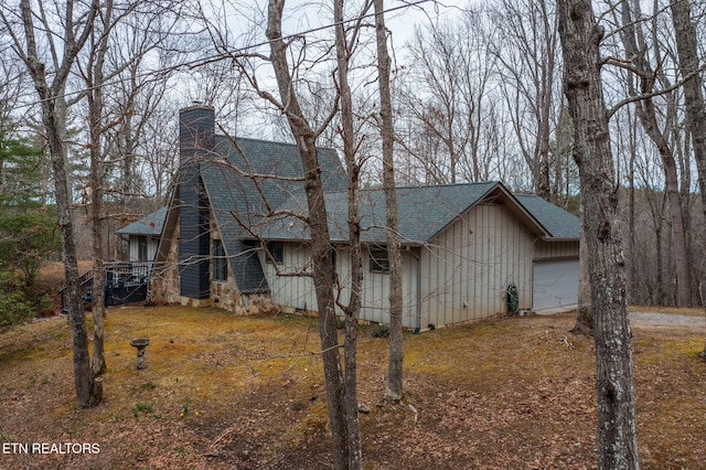 view of front facade with a chimney, a garage, and roof with shingles