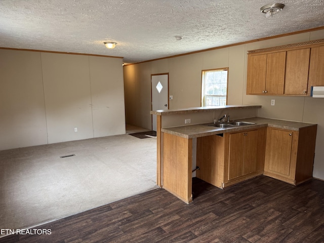 kitchen with brown cabinetry, dark wood-style floors, a peninsula, crown molding, and a sink