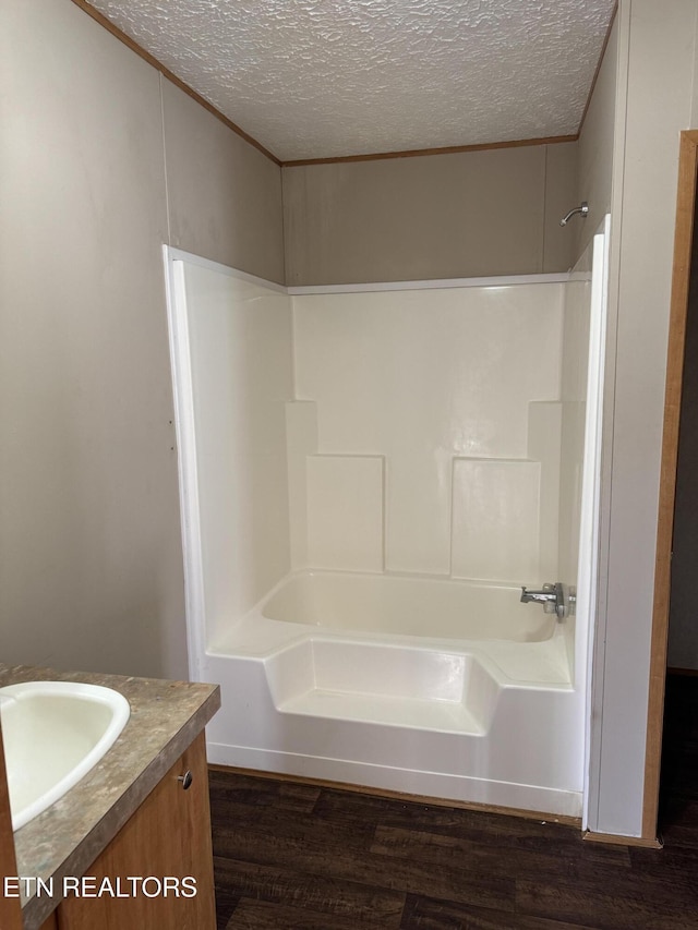 full bathroom with shower / bathing tub combination, a textured ceiling, vanity, and wood finished floors