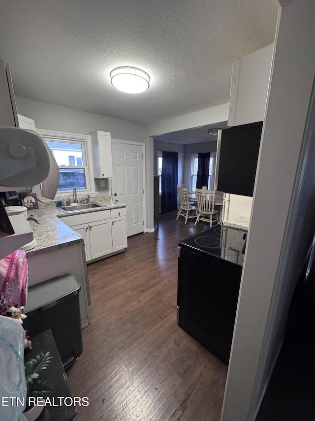 kitchen with dark wood finished floors, a sink, white cabinets, black range with electric cooktop, and a textured ceiling