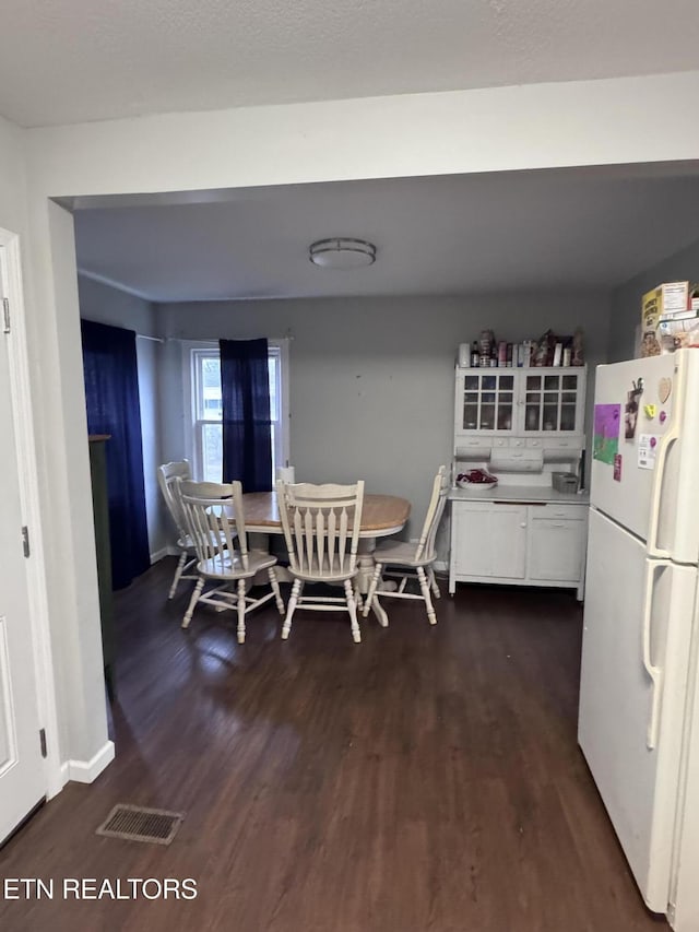 dining space featuring dark wood finished floors, baseboards, and visible vents