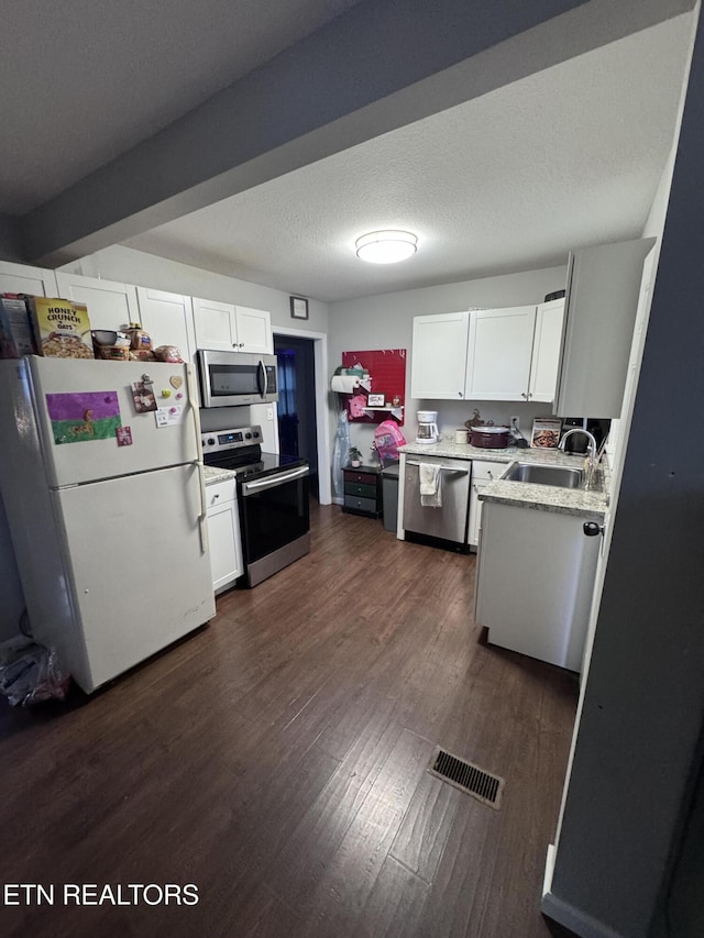 kitchen featuring visible vents, a sink, stainless steel appliances, dark wood-type flooring, and a textured ceiling