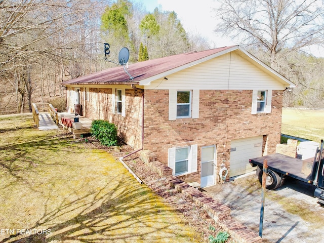 exterior space featuring a garage, driveway, a lawn, and brick siding