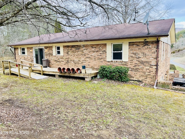 back of house with a deck, a yard, and brick siding