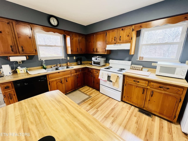 kitchen featuring white appliances, visible vents, light countertops, under cabinet range hood, and a sink