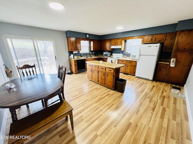 kitchen with under cabinet range hood, white appliances, a kitchen island, a sink, and light wood finished floors