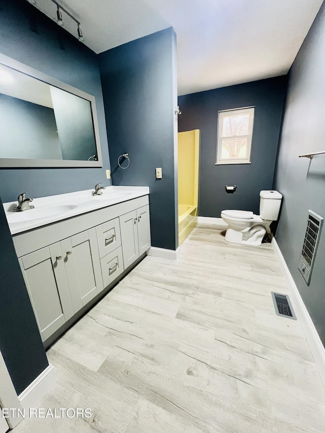 full bathroom featuring toilet, wood finished floors, a sink, visible vents, and baseboards