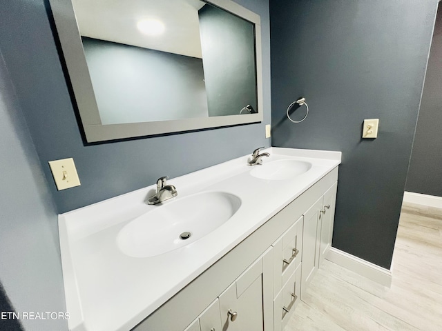 bathroom featuring double vanity, a sink, baseboards, and wood finished floors