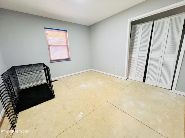 unfurnished bedroom featuring a closet, concrete floors, and baseboards