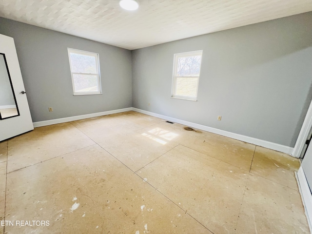 spare room featuring a healthy amount of sunlight and baseboards