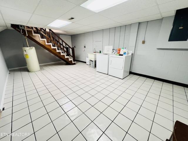 finished basement featuring electric panel, a drop ceiling, stairs, washer and dryer, and water heater