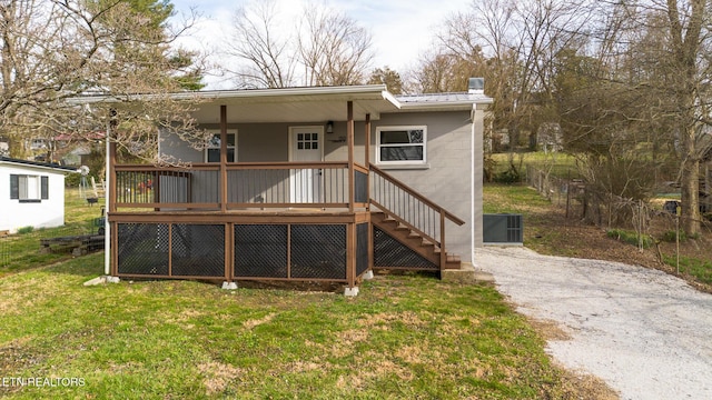 back of property featuring metal roof, stairway, aphalt driveway, and a yard