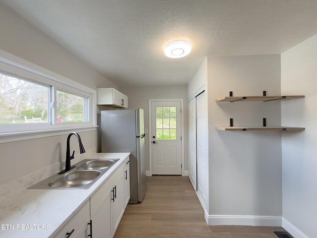 kitchen with light countertops, a healthy amount of sunlight, white cabinets, and a sink