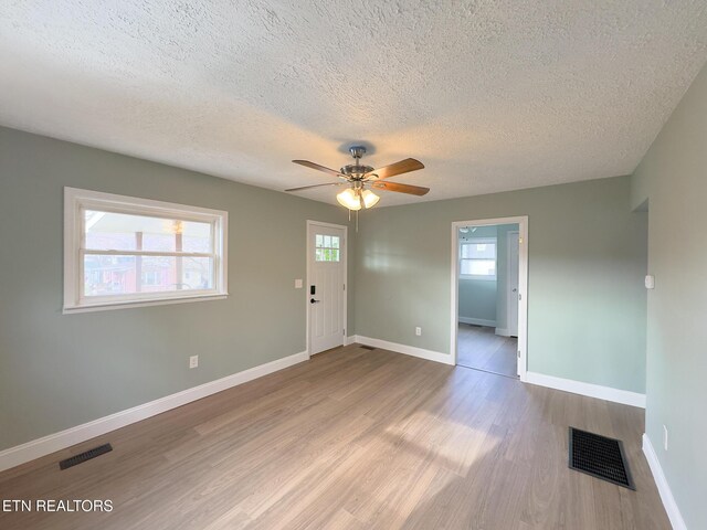 interior space featuring a ceiling fan, wood finished floors, visible vents, and baseboards