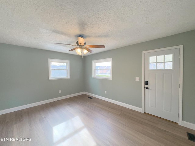 foyer entrance featuring visible vents, ceiling fan, baseboards, and wood finished floors