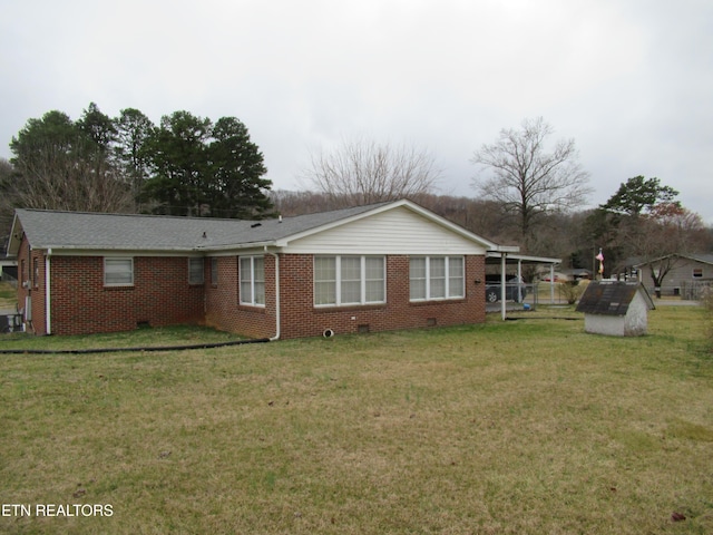 back of property with crawl space, a yard, and brick siding