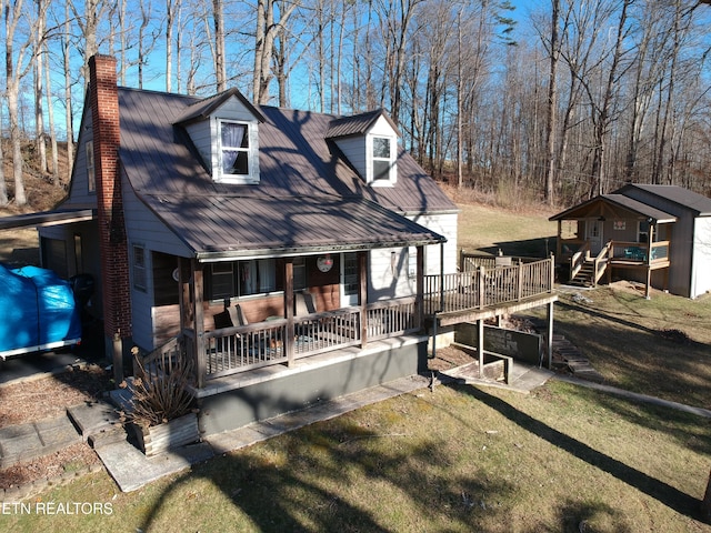 view of front of home with a front lawn, covered porch, and a chimney