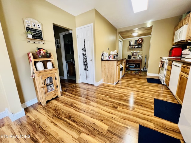 kitchen with light wood-style flooring, white appliances, and baseboards