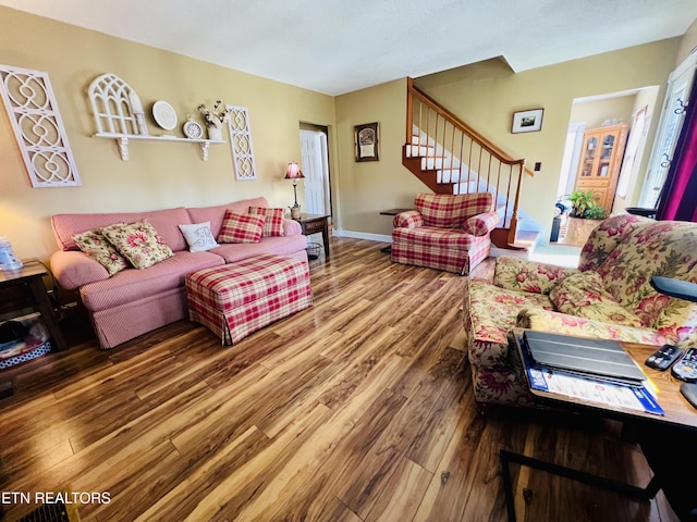 living area featuring stairway, baseboards, and wood finished floors