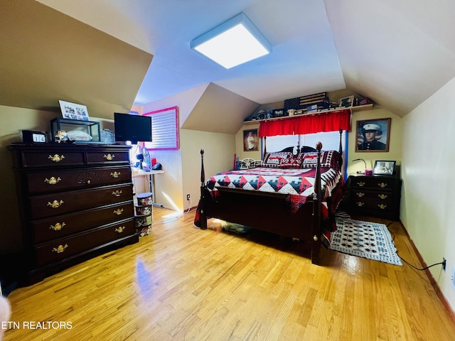 bedroom featuring lofted ceiling, baseboards, and light wood-type flooring