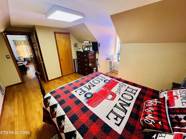 bedroom featuring lofted ceiling, wood finished floors, and baseboards