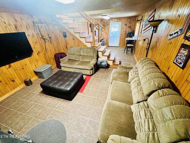 living room with tile patterned floors, wooden walls, stairs, and baseboards