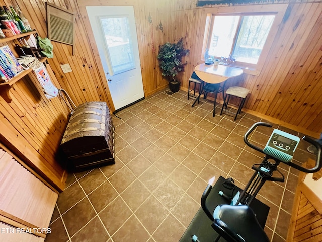 tiled living area featuring a wealth of natural light, baseboards, and wooden walls