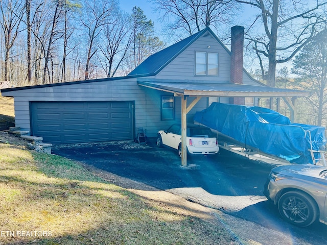 view of property exterior with a carport, driveway, and a chimney