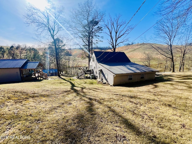 view of property exterior with metal roof, a yard, a mountain view, and stairway