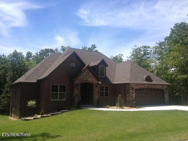 view of front of home with a front lawn, stone siding, a garage, and driveway