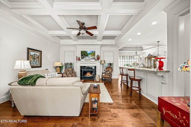 12 Inwood Dr, Fairfield Glade, TN 38558 - living room featuring beamed ceiling, a lit fireplace, ceiling fan with notable chandelier, dark wood-style floors, and coffered ceiling