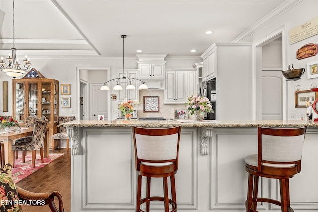 12 Inwood Dr, Fairfield Glade, TN 38558 - kitchen featuring a breakfast bar area, ornamental molding, light stone counters, decorative backsplash, and dark wood-style flooring