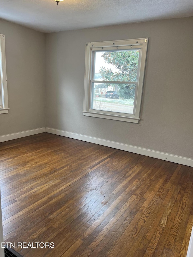 empty room featuring dark wood-style floors, baseboards, and a textured ceiling