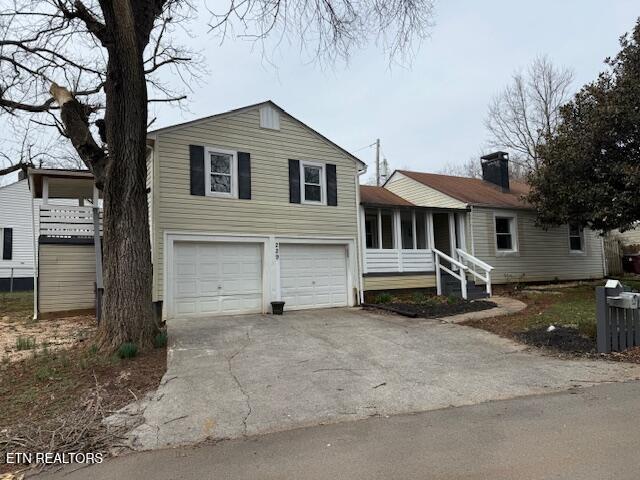 tri-level home with a chimney, concrete driveway, and a garage