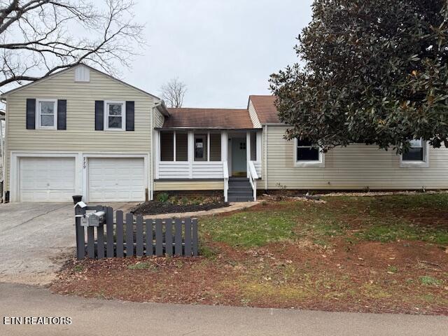 tri-level home with an attached garage, driveway, and roof with shingles