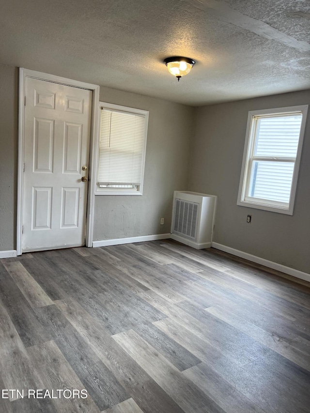 spare room with visible vents, baseboards, a textured ceiling, and wood finished floors