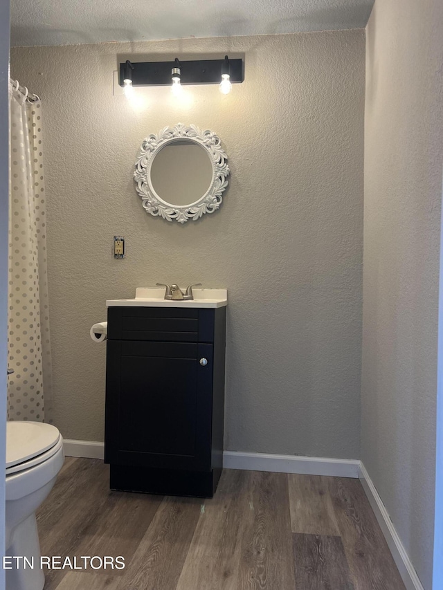 full bathroom featuring vanity, wood finished floors, baseboards, curtained shower, and toilet