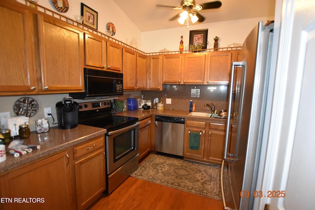 kitchen featuring a sink, backsplash, dark wood-style floors, stainless steel appliances, and brown cabinetry