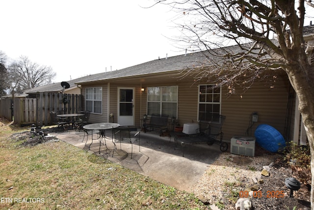 rear view of house featuring a patio area, fence, and roof with shingles