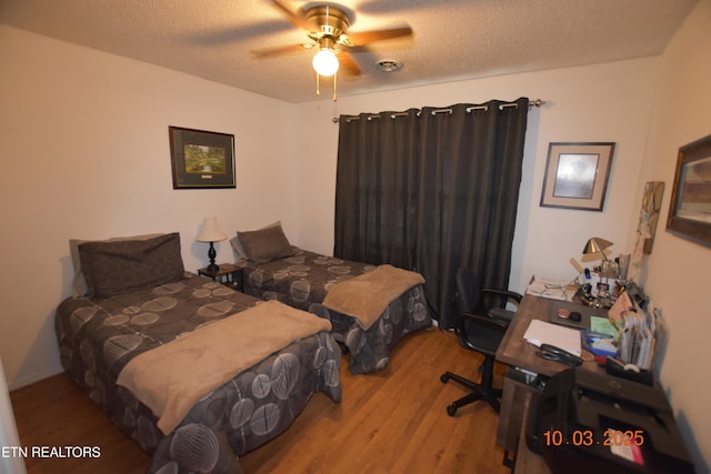 bedroom with ceiling fan, wood finished floors, and a textured ceiling