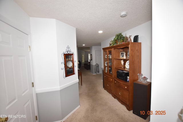 corridor featuring a textured ceiling, recessed lighting, and light carpet