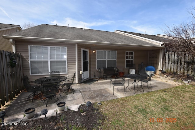 rear view of property featuring a yard, a patio, a shingled roof, and fence